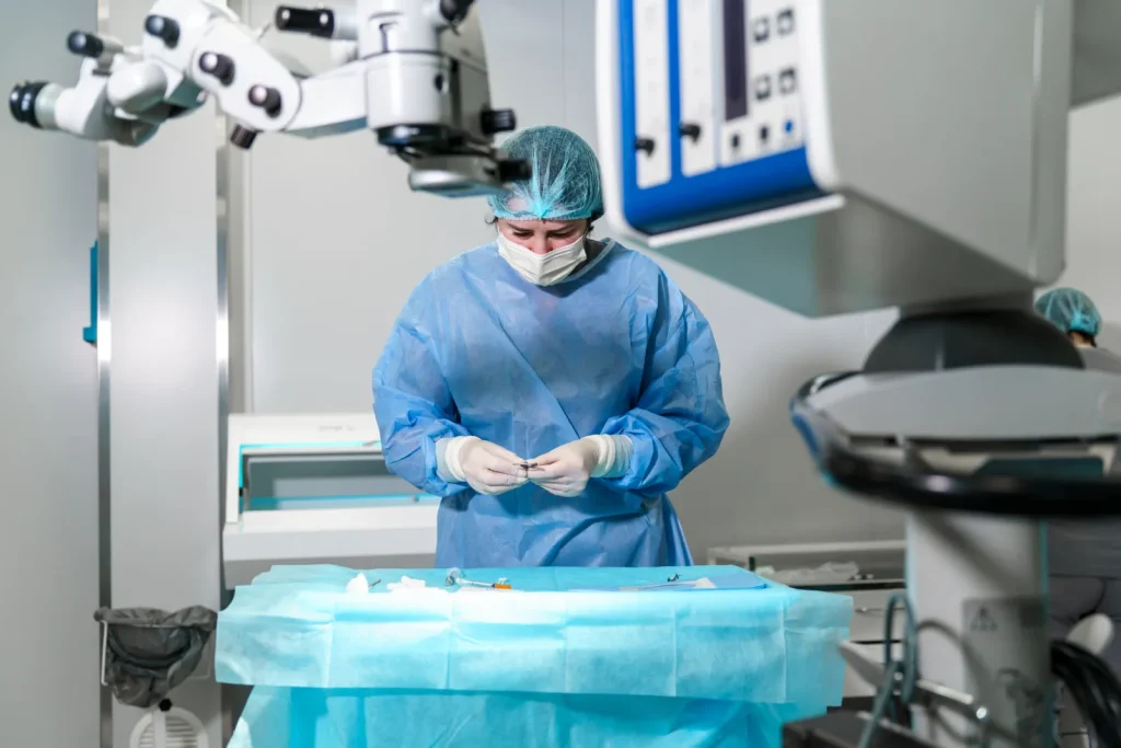 Surgeon preparing instruments beneath an operating microscope